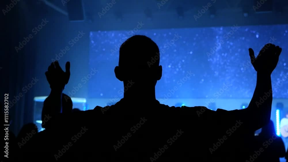 A man singing worship songs lifting his hands up in church. Praising God.