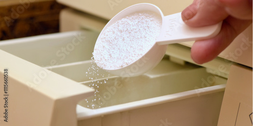 Closeup of woman's hand adding laundry conditioner to a washing machine compartment