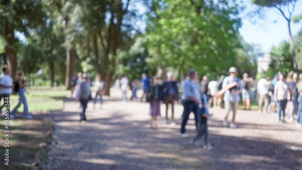 Blurry crowd at villa borghese gardens in rome with trees bokeh and sunlit pathways in an outdoor serene atmosphere. Blurry crowd at villa borghese gardens in rome with trees bokeh and sunlit pathways in an outdoor serene atmosphere.
