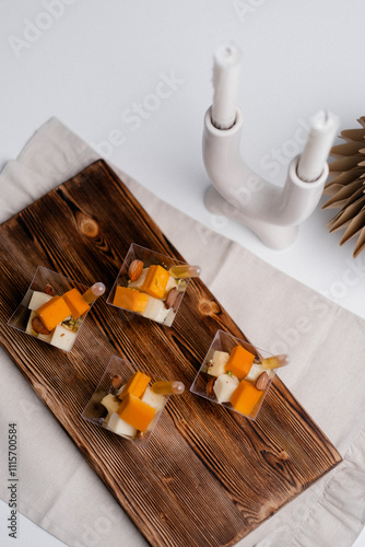 The image showcases an elegant food display with four small, clear plastic cups on a wooden serving tray