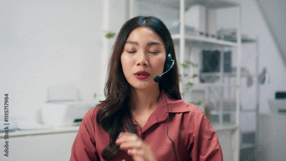 Friendly Asian woman working as a customer support operator with a headset in a call center office. Portrait of female sales agent talking to client working at desk. Customer service representative. Friendly Asian woman working as a customer support operator with a headset in a call center office. Portrait of female sales agent talking to client working at desk. Customer service representative.