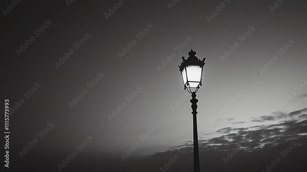 A black and white photo of a streetlight with a cloudy sky in the background.