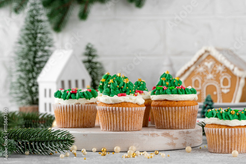 Christmas tree and wreath shaped cupcakes with candy sprinkles on top. Christmas dessert on a light concrete background.