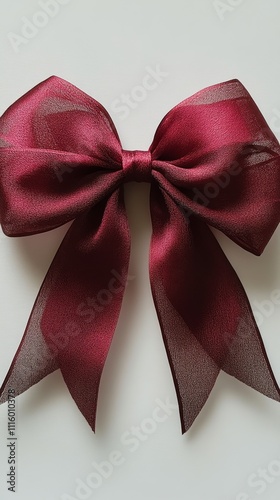 Elegant maroon bow with textured fabric on light marble surface surrounded by...
