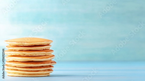Stacked pancakes with a light blue background for a breakfast setting