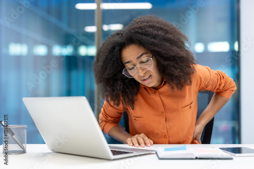 Vászonkép Young businesswoman feeling discomfort due to back pain at her desk