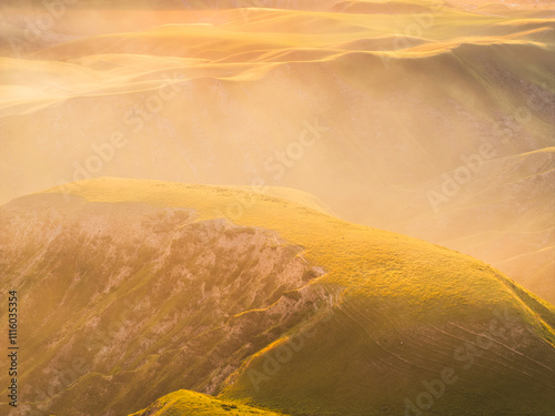 Drone view of mountains at sunset. Beautiful golden clouds covered the earth. Evening landscape.