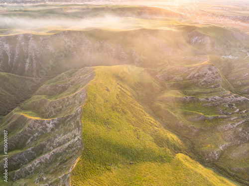 Drone view of mountains at sunset. Beautiful pink and white clouds covered the earth. Evening landscape.