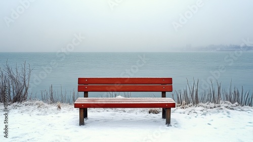 Snow covered bench by the foggy lake in winter landscape