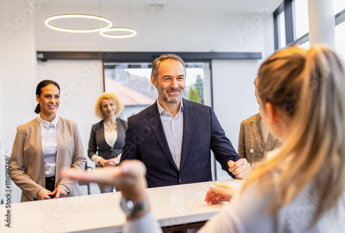 Businessman arriving in a hotel with his colleagues for a business conference, checking in at the reception.