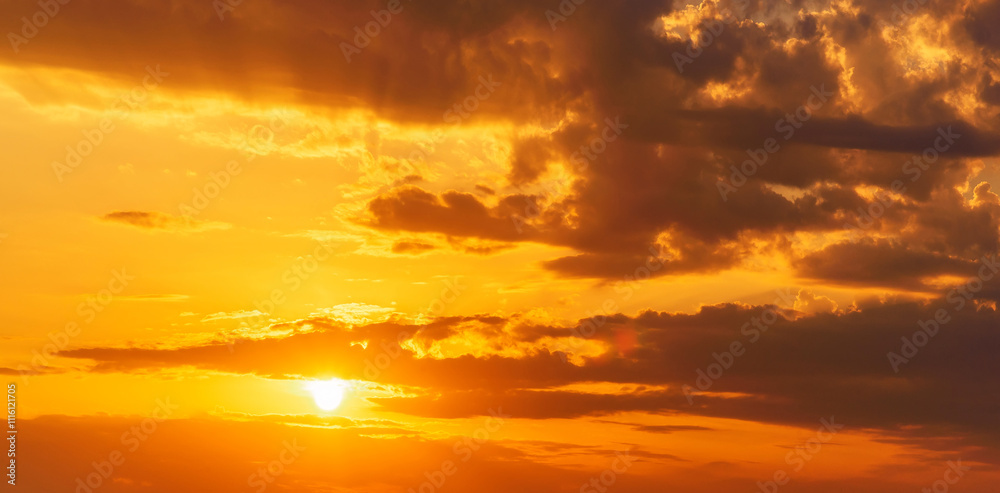 Obraz premium Panorama with an orange sunset and the sun in a cloudy sky with clouds