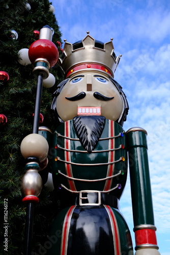 Close-up photo of a large nutcracker in front a large Christmas tree