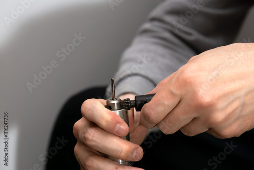 Replacing the nozzle on the burr grinder, men's hands with engraver close-up.  photo