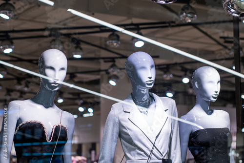 In a store window, there are three mannequins being displayed artistically photo