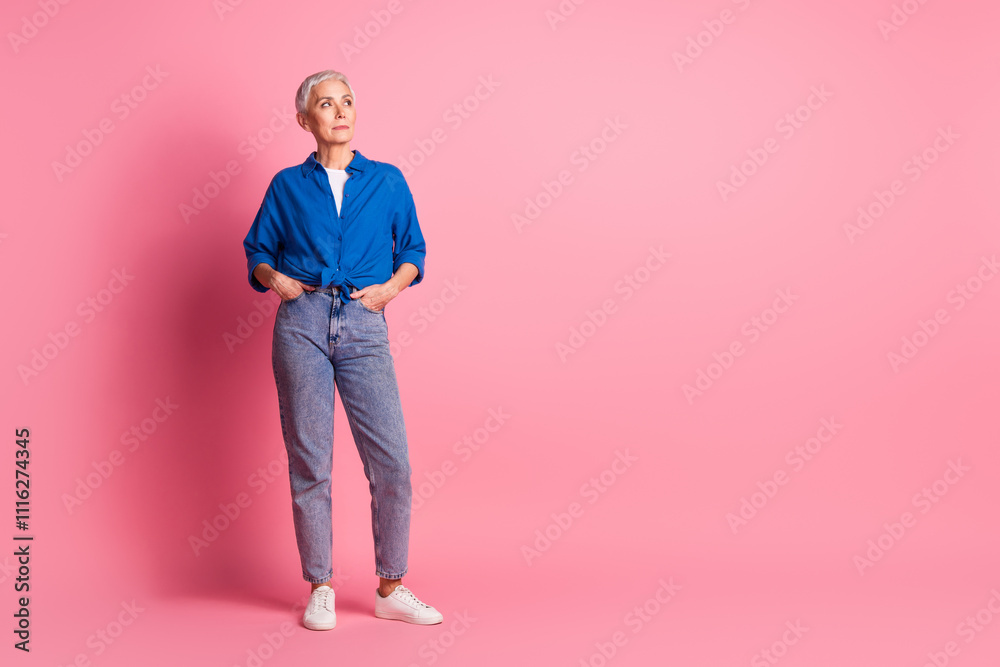 Full length photo of cheerful pretty lady dressed blue shirt smiling looking empty space isolated pink color background Full length photo of cheerful pretty lady dressed blue shirt smiling looking empty space isolated pink color background