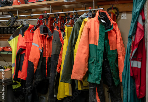 Various colorful protective work jackets hanging on a rack in a workshop, with tools and equipment in the background. Concept of safety gear photo