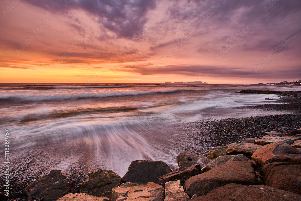 Obraz premium As the sun sets over San Lorenzo Island, the view from Miraflores becomes pure magic .The island silhouettes against a sky ablaze with color, while the ocean whispers of infinite horizons. 