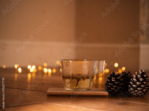 Cup of chamomile tea with pine cones with twinkling lights bokeh