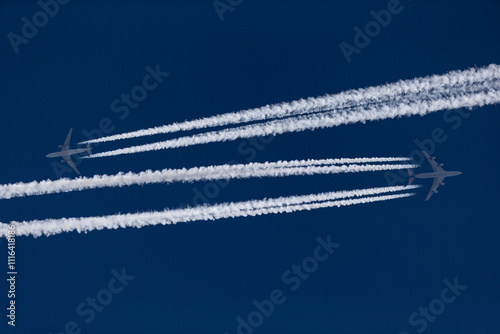 Two air planes with white condensation trails at the deep blue sky