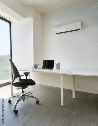Office desk with computer equipment on it and also office chair located in an office room with bright white walls