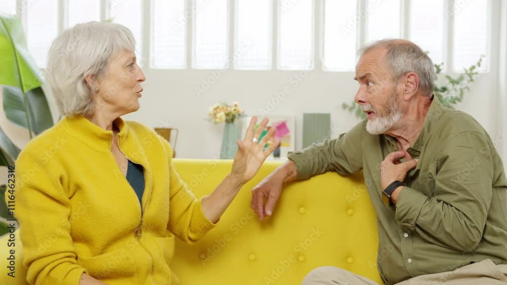 Mature couple engaging in a heated argument while sitting on a yellow sofa Stock ビデオ | Adobe Stock