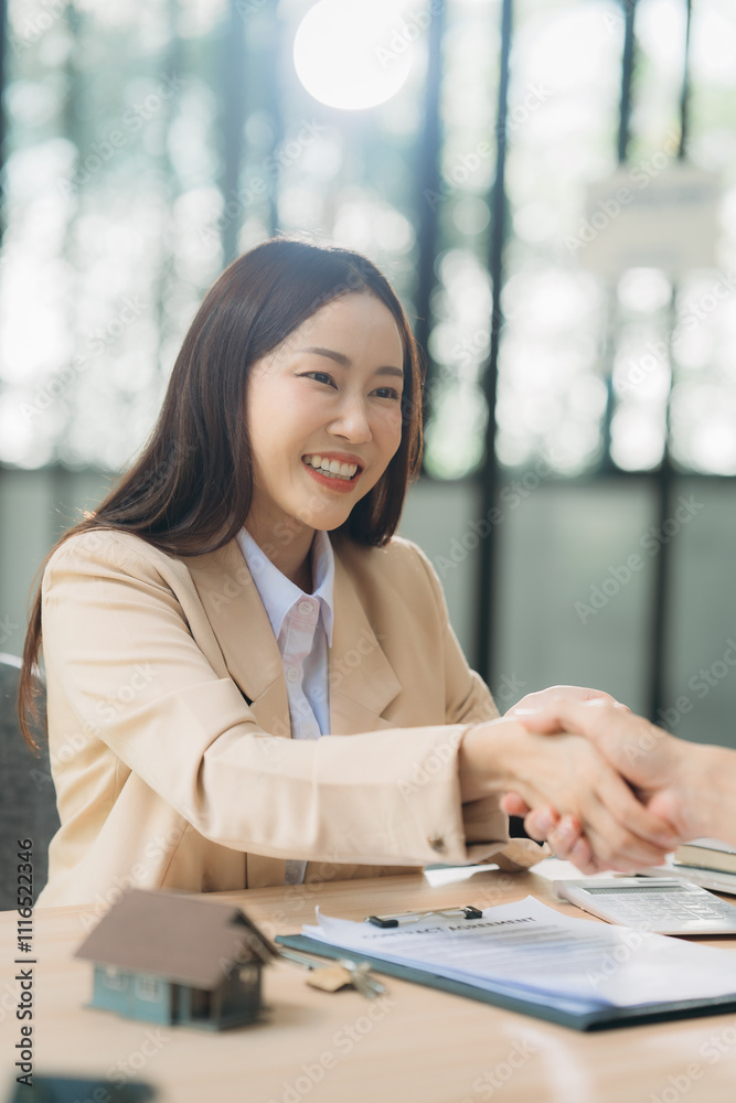 Obraz premium Successful Real Estate Deal: Smiling businesswoman shaking hands, closing a deal. House model and keys on table