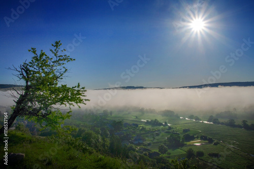 sunrise, rays in the blue sky, panorama landscape in the fog, view of the set...