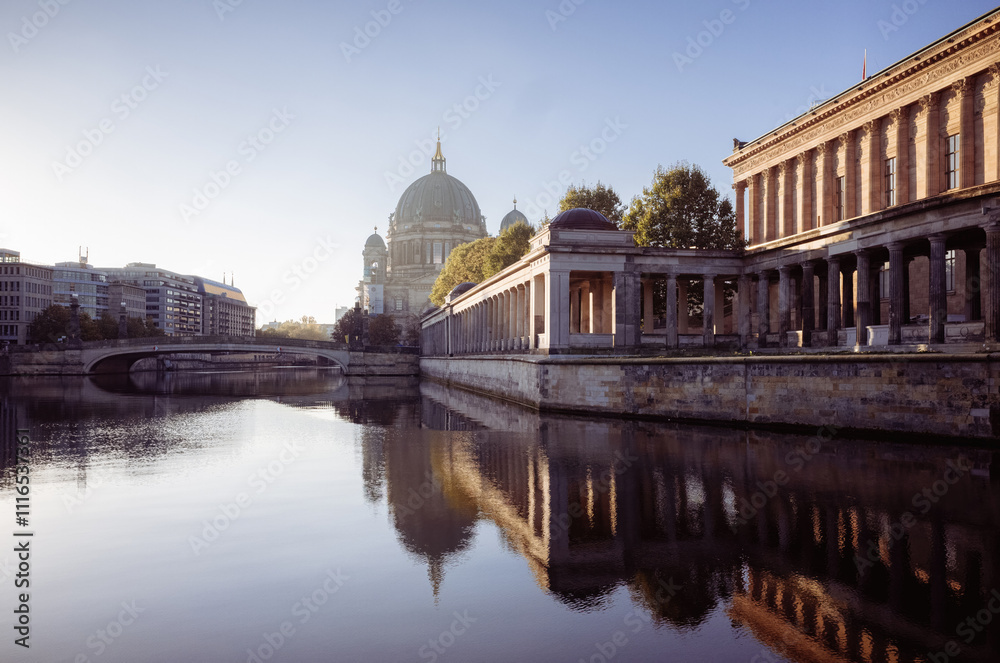 Fototapeta premium view of Museum Island in Berlin during sunrise, with Berlin Cathedral n the background. calm waters of the Spree River reflect the historical architecture