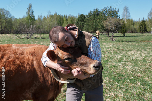 Farmer hugging a cow on a farm close-up. Summer.