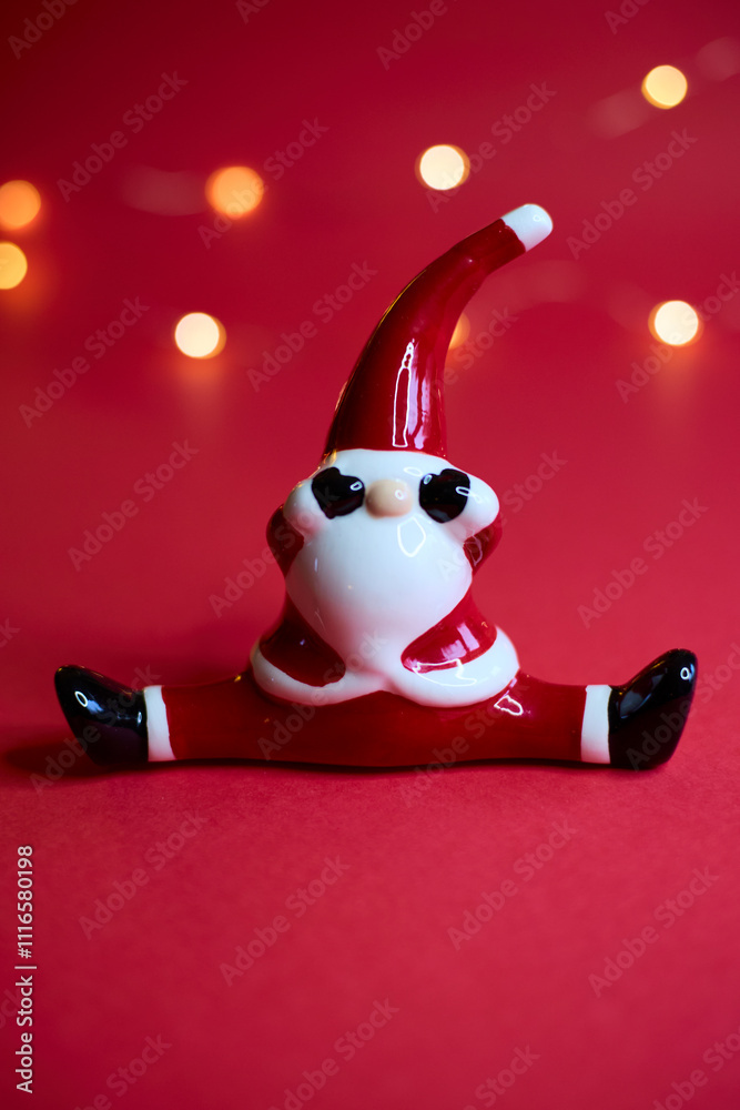 A festive Santa figurine is beautifully set against a red background with shimmering bokeh