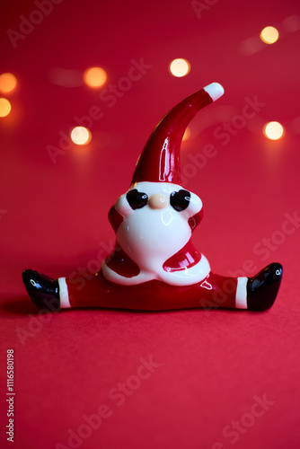 Obraz na płótnie A festive Santa figurine is beautifully set against a red background with shimmering bokeh w salonie