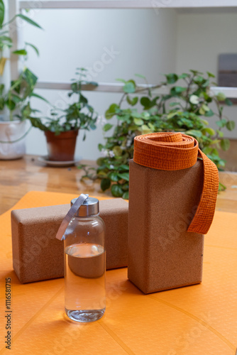 Hydration and wellness: yoga props on an orange mat in a tranquil space. 