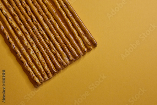 Obraz na płótnie Deliciously Crispy Pretzel Sticks Set Against a Bright Yellow Background for Visual Appeal w salonie