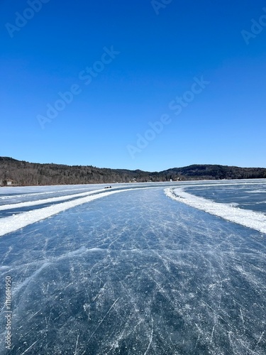 Frozen Lake with Ice Tracks Under Clear Blue Sky