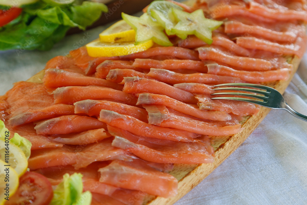 Freshly prepared salmon dish garnished with citrus and vegetables served on a wooden platter at a sunny outdoor setting Freshly prepared salmon dish garnished with citrus and vegetables served on a wooden platter at a sunny outdoor setting
