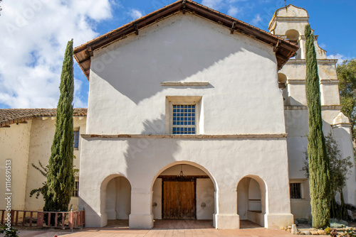 Spanish style mission building next to bell tower, adobe clay tiles, daytime, nobody	