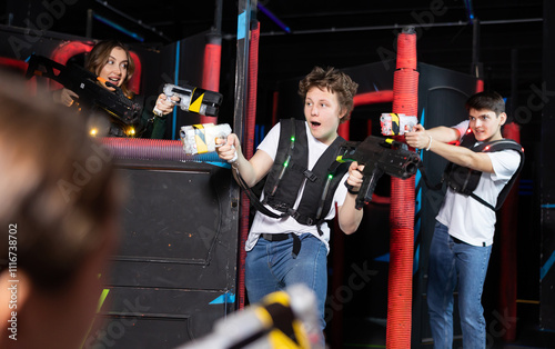 Two guys and one girl running and dodging while playing lasertag photo