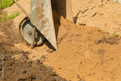 Construction wheelbarrow filled with sand work with a shovel