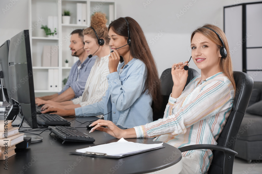 Team of technical support agents working with computers at table in office Team of technical support agents working with computers at table in office