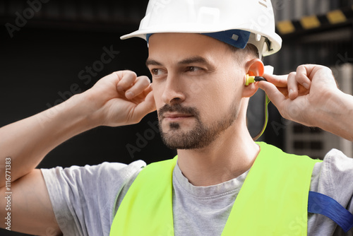 Foto Male builder putting in earplugs outdoors, closeup