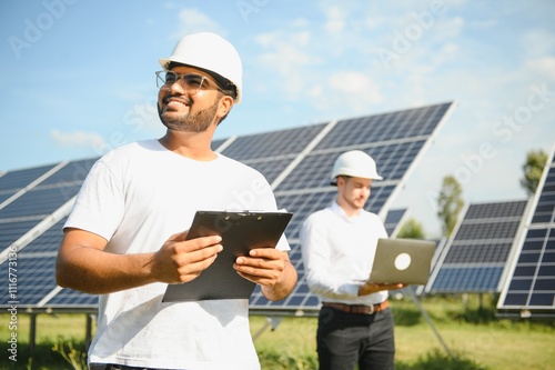 Solar power plant with two engineers walking and examining photovoltaic panels. Concept of alternative energy and its service photo