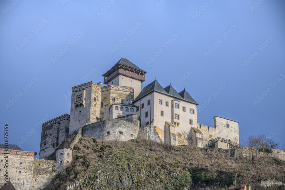 Fototapeta premium Trencin Castle on a hilltop under a clear blue sky, showcasing its historic architecture.