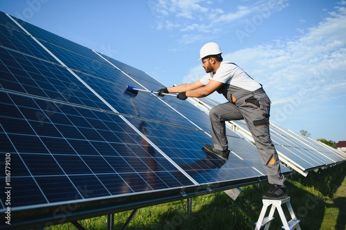 Indian handyman cleaning solar panels form dust and dirt photo