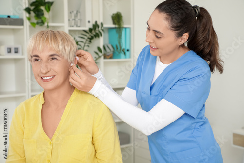 Wallpaper Mural Doctor putting hearing aid on mature woman's ear in clinic Torontodigital.ca