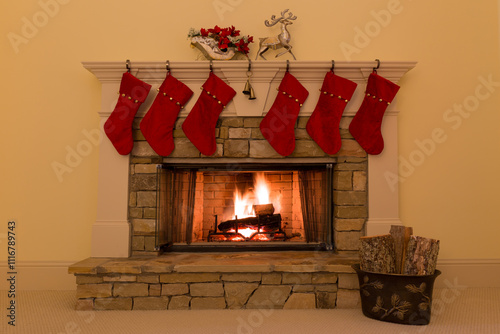 Six red Christmas stockings adorn a stone fireplace with a cozy fire.