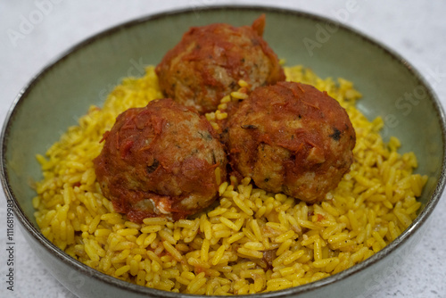 Traditional mediterranean dish. Closeup view of hake fishballs with tomato sauce and rice with saffron, in a bowl 