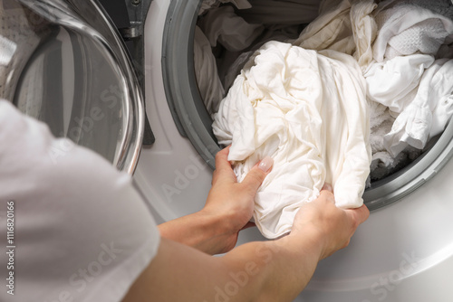 Woman taking clean clothes out of washing machine, closeup