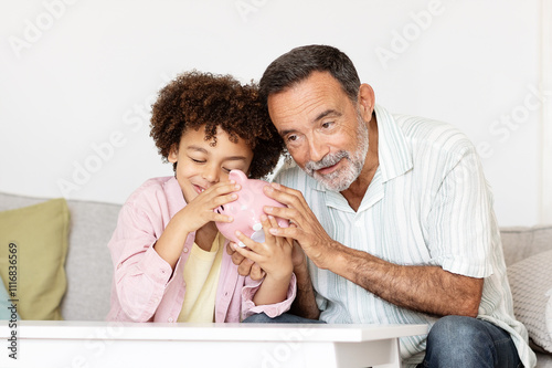 Obraz na płótnie A grandfather and his grandson are sitting together on a couch at home, sharing a moment of bonding