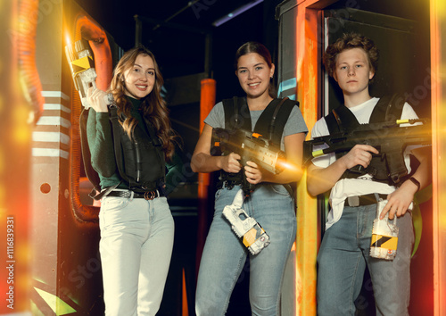 Joyful people posing with laser guns having fun on dark lasertag arena