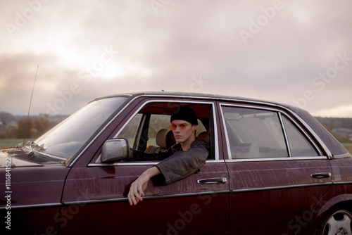 A man sits in an old car photo